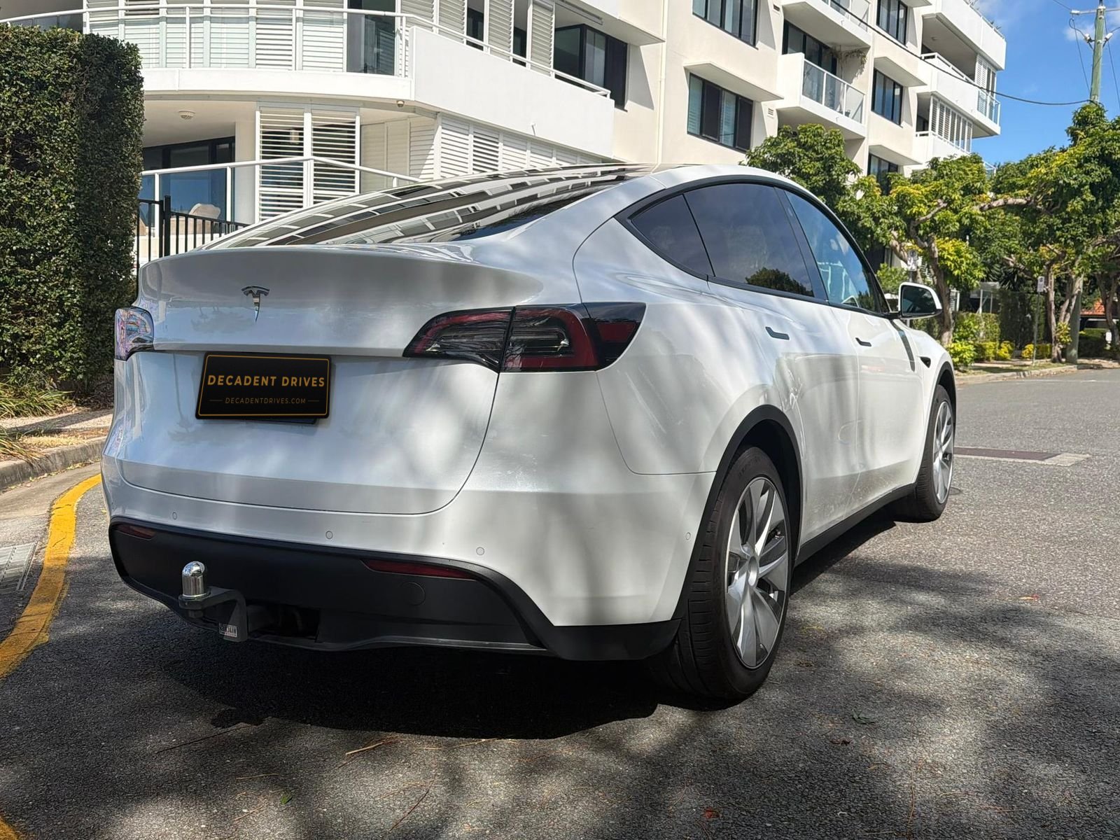 White 2022 Tesla Model Y electric SUV, rear three-quarter view – Decadent Drives hire car, Brisbane