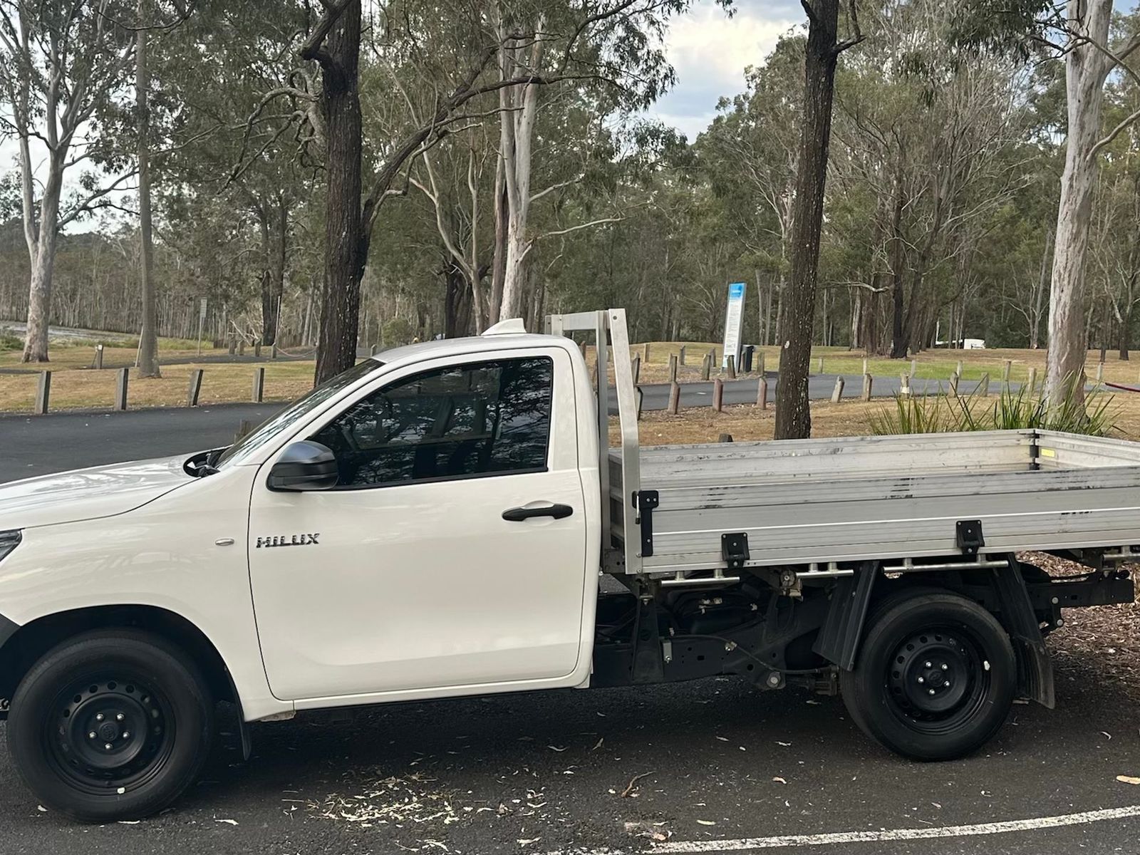 White 2022 Toyota Hilux single-cab tray ute, side view of the alloy tray among gum trees