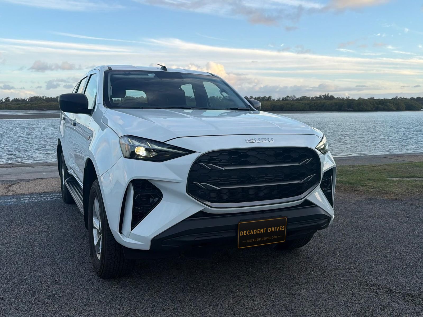 White 2025 Isuzu MU-X 7-seat SUV, front three-quarter view by the water – self-drive hire in Brisbane